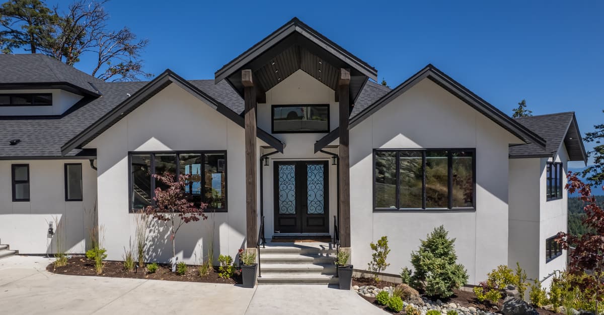 White custom home with timber pillars and wrought iron front door