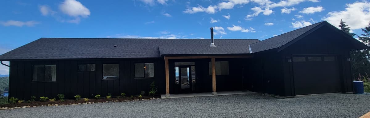 All-black metal siding home with timber porch entry